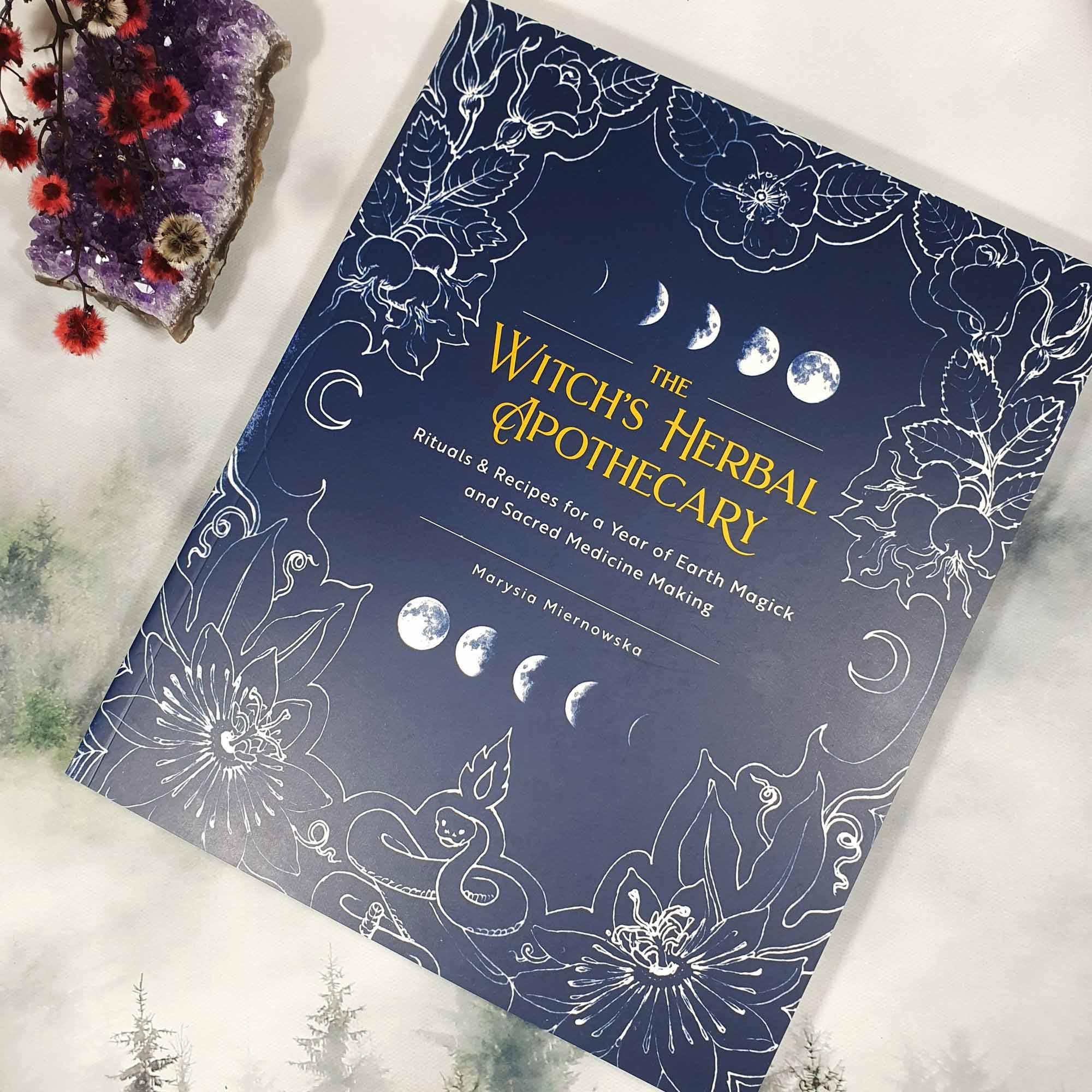 Black bottle of Sacred Body Oil with golden label and oil droplets.